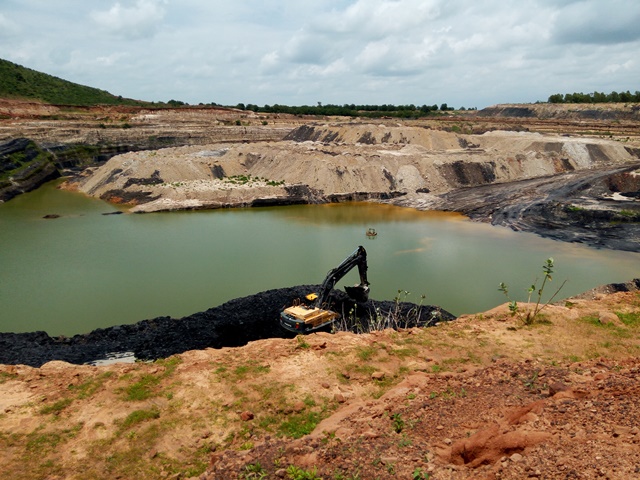 An excavator collects mined coal at the Maiganga coal mine