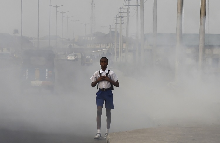 A school boy walks past smoke and fumes emitted from a dump in the city of Port Harcourt, Rivers State, on February 14, 2017. Credit: PIUS UTOMI EKPEI/AFP/Getty Images)