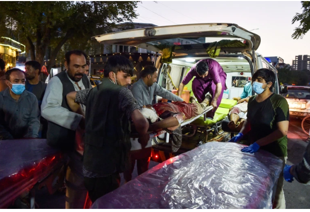 Volunteers and medical staff bring an injured man for treatment after multiple explosions killed at least 60 people, outside the airport in Kabul on August 26, 2021 (Wakil Kohsar/AFP)
