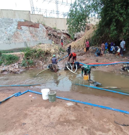 People try to fetch water as machine operators do their job
