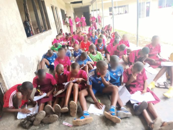 Students sitting on bare floor to write Examination at Secondary Grammar School, Upenekang, Ibeno. Credit: Ekemini Simon.