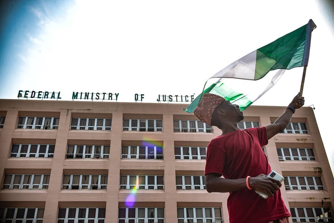 A protester waves the national flag of Nigerian flag during an #EndSARS demonstration outside of the Ministry of Justice in Abuja in October 2020. Photo by Dawali David