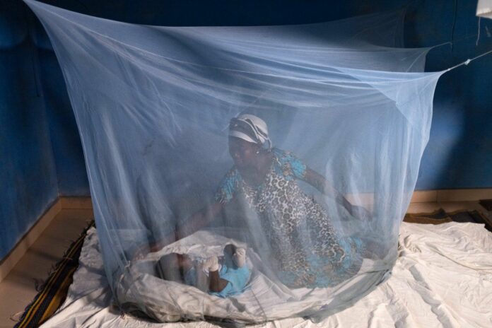 File photo of a mother nursing her child under Intermittent Treated Net. Photo: WHO