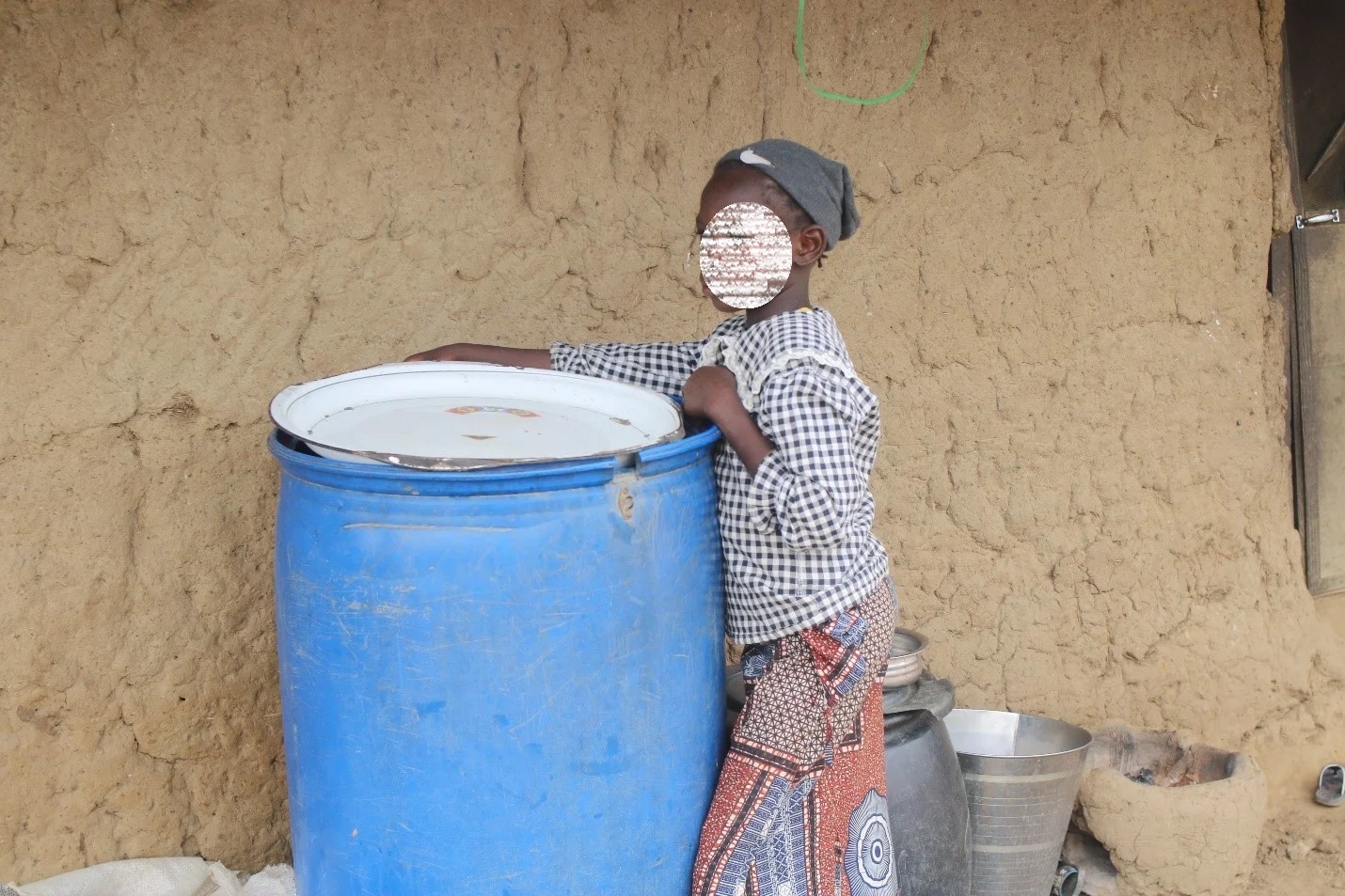 Fati standing beside an empty drum                                                                                           Photo: Emmanuel Adegoke