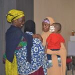 Aisha Ahmad holding her baby, and two participants at the training venue.