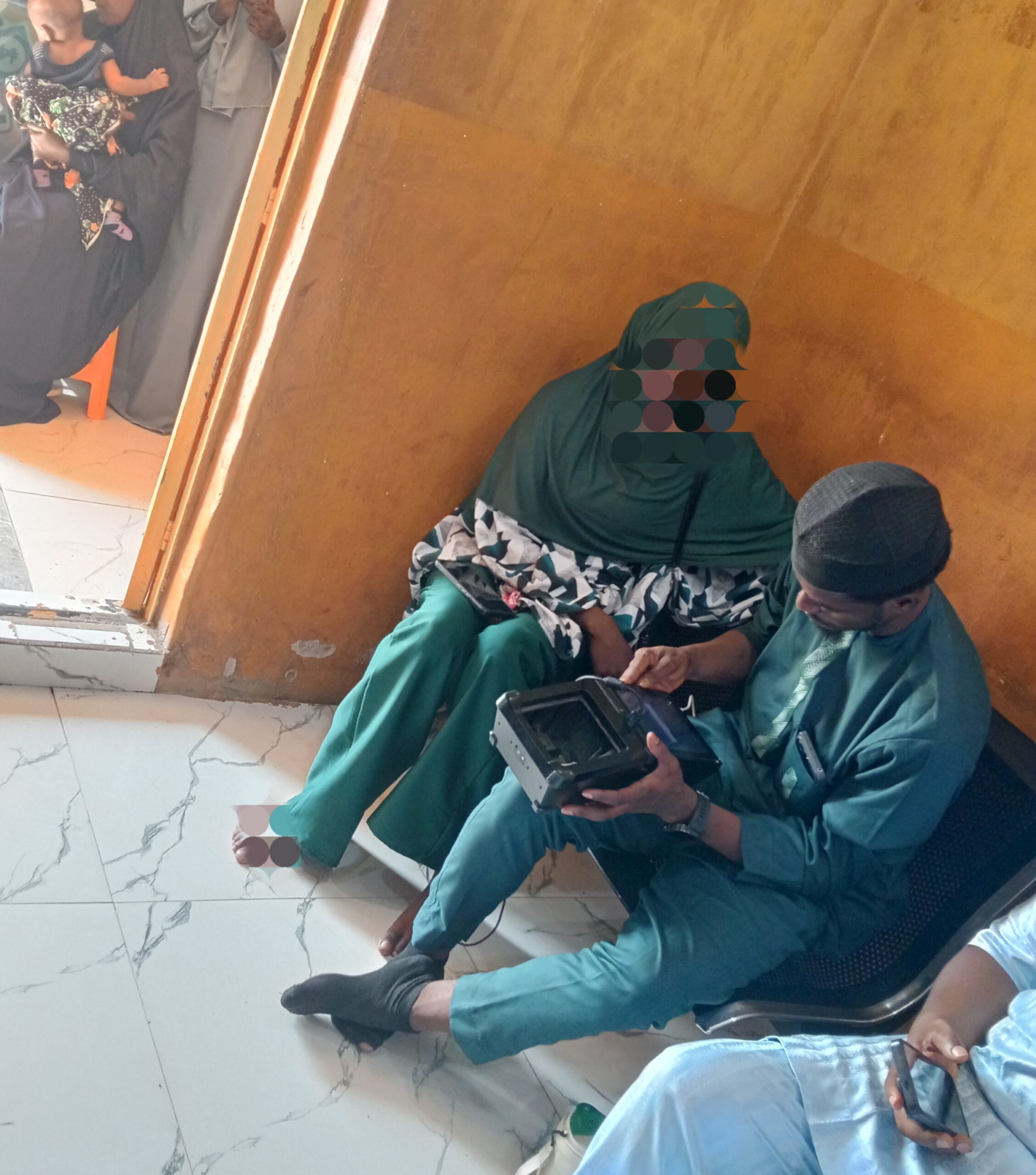 Fati and NIN agent during the enrollment in his-shop in-Dei-Dei.-PC-Hamzat Ibrahim Abaga/ICIR